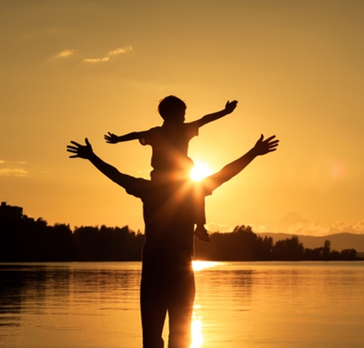 dad carrying son in the sun